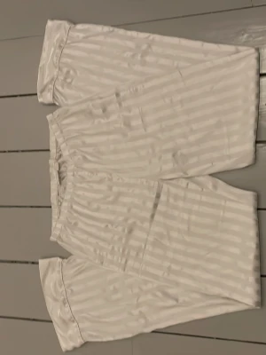 Randig pyjamas byxa från Gina Tricot - Säljer en vit pyjamas byxa med subtila, blanka ränder från Gina Tricot. Materialet känns svalt och mjukt mot huden. 