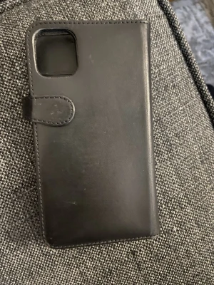 plånboksfodral/telefonskal - Stilrent svart plånboksfodral i konstläder till iPhone 11. Fodralet har magnetlås och öppning för kameran. Perfekt för dig som vill skydda mobilen och samtidigt ha plats för kort. Passar modeller med större kameralins. 