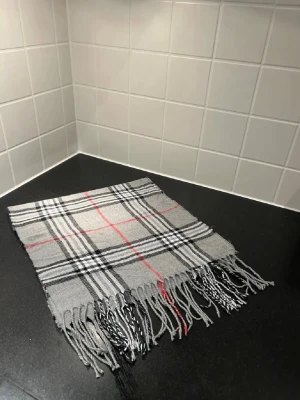 Grå Burberry scarf  - Burberry scarf i klassiskt rutmönster. Helt ny och aldrig använd. Självklart äkta. Väldigt snygg och passar till typ allt.