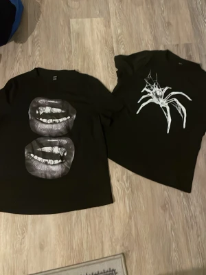 T-Shirts med tryck  - Två svarta t-shirts från SHEIN i storlek M. Ena har ett tryck med två läppar och den andra har en vit spindel med spindelnät. Båda är kortärmade och har en loose fit. Dom är lite kortare än en vanlig T-shirt 