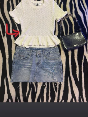 Vit volangblus från H&M Divided XS - Supersöt vit blus från H&M Divided i storlek XS. Toppen har korta ärmar, rund hals och en volangkant nedtill som ger en peplum-effekt. Materialet är stickat med struktur och består av 78% polyester och 22% bomull. Perfekt till jeans eller kjol!