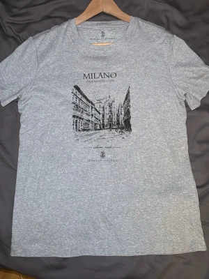 Grå Milano t-shirt Brunello Cucinelli - Snygg grå t-shirt från Brunello Cucinelli med Milano-tryck och skissad stadsmotiv på bröstet. Org pris ligger runt 4k denna är endast använd enstaka ggr