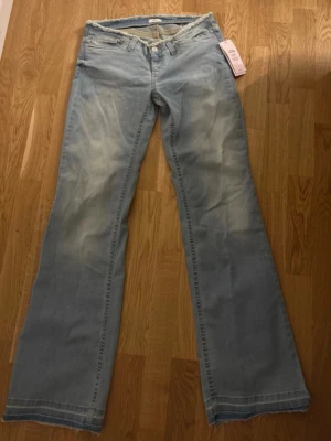 Blå bootcut jeans från Nelly, EU 38 - Säljer ett par ljusblå bootcut jeans från Nelly i modellen 'No Waist Bootcut Jeans'. Jeansen har råa, fransiga kanter i midjan och vid bensluten för en edgy look. Klassisk femficksmodell i mjukt bomullsmaterial. Perfekta för dig som gillar statement-jeans. Pris kan även diskuteras. 