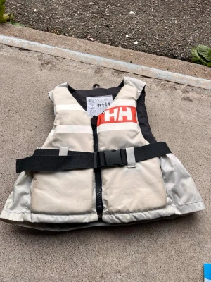 Flytväst HH - Helly Hansen flytväst inköpt 2023. Fint skick! Endast lite missfärgning men inget som påverkar funktion! Tre säkerhets steg - dragkedja, spänne samt snörning. CE märkt. Storlek xxs, 30-40kg.
