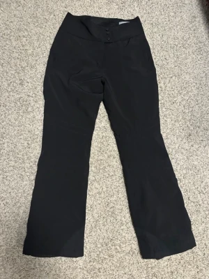 Svarta skidbyxor Cross Sportswear  - Säljer ett par svarta täckbyxor från Cross Sportswear i storlek M. Byxorna har hög midja,  knappt använda, resår bak och dragkedja längs benen bak.Tillverkade i ett slitstarkt syntetmaterial som passar perfekt för vinterns aktiviteter. Knappt använda. Pris kan diskuteras!