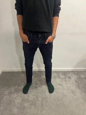 Replay jeans  - Mörkblå Replay jeans med smal passform och klassiska fem fickor. Snygga kontrastsömmar och detaljer på bakfickorna. Jeansen har låg midja och är tillverkade i stretchigt jeansmaterial för en bekväm känsla. W30 L30