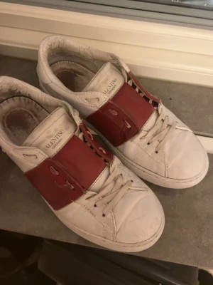 Valentino skor - Säljer dessa Valentino Open sneakers i storlek 40! Använda men fortfarande i okej skick. De har varsit litet hål vid hälen på insidan av skon som lätt går att lösa om man köper ett ilägg man kan klistra fast, inget som syns eller märks när de används. Skorna har andra defekter som att lädret spruckit och repats på vissa ställen, som syns på tredje bilden. Har tyvärr ingen dustbag eller box, därav priset. Kom gärna med frågor eller fler bilder! Pris går att diskuteras vid snabbaffär!