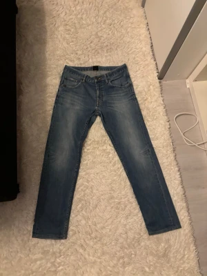 Tiger of Sweden Jeans Iggy Blå - Säljer ett par klassiska blå jeans från tiger of sweden. Jeansen har fem fickor, normal passform och snygg tvättad look med ljusa partier. Perfekta till vardags och passar till det mesta. Midjan är inte så stor enligt mig och materialet är slitstarkt . En av mina gamla favoriter! BILLIGARE VID SNABB AFFÄR.