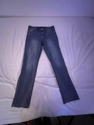 Blå raka jeans från LMTD, strl 14S - Säljer ett par klassiska blå jeans från LMTD i storlek 14S. Jeansen har rak passform, fem fickor och normal midja. Materialet är slitstarkt jeans med snygg tvätt och subtila slitningar vid låren. Perfekta till sneakers eller boots.