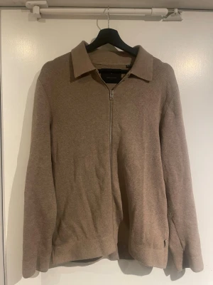 Beige kofta med dragkedja Jack & Jones - Säljer en stilren beige kofta från Jack & Jones Premium. Koftan har dragkedja framtill, klassisk krage och är långärmad. Materialet är mjukt och stickat, perfekt för lager på lager under höst och vår. Enkel att matcha. Hör av dig vid frågor!