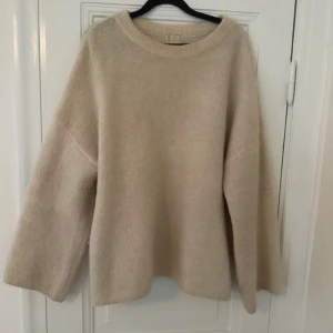 Beige oversized mohairtröja H&M - Supermjuk och fluffig beige stickad tröja från H&M i mohair- och ullmix. Tröjan har en relaxed oversized passform, rund halsringning och långa ärmar. Perfekt för lager på lager under kyliga dagar.