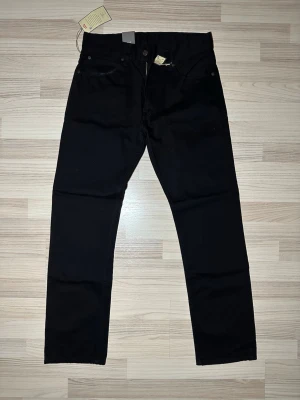 Svarta Pearson 636 Standard Fit Jeans - Säljer ett par svarta Pearson 636 jeans med standard fit. Klassisk femficksmodell med raka ben och snygg passform. Jeansen har läderpatch bak i midjan och tydliga etiketter. Perfekta till en clean och stilren look.