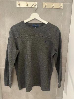 Stickad Ralph lauren tröja - Säljer en grå Ralph lauren tröja med ett mörkblått Ralph lauren märke. De är en sjukt snygg tröja som sitter slim fit. Tröjan är XL men det är barnstorlek så de är som XS/170cm. Skick 10/10 nypris 1299kr säljs för 499kr pris kan diskuteras!