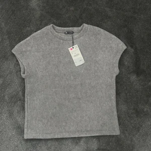 Grå ärmlös topp från Zara - Säljer en grå stickad t-shirt från Zara i ärmlös modell med rund halsringning. Storlek S. Tröjan är i helt nytt skick där av att prislappen är kvar💕💕
