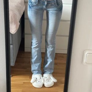 Sky eagle low waist bootcut jeans - Säljer ett par ljusblå bootcut jeans med snygga slitningar och klassiska fickor bak. Jeansen har låg midja och är tillverkade i stretchigt material för en bekväm passform. Innerbenslängd: 86 cm💕