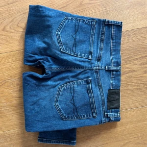 Blå skinny jeans Polo Ralph Lauren - Storlek 160. Snygga blå jeans från Polo Ralph Lauren med klassisk femficksdesign och smal passform. Jeansen har mörk tvätt, svarta detaljer på knappar och logga på fickan. Perfekta för dig som gillar en stilren och tidlös look. 