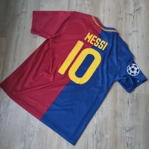 FC Barcelona Messi 10 Nike fotbollströja - Säljer en klassisk FC Barcelona fotbollströja från Nike med Messi 10 på ryggen. Tröjan är tvåfärgad i rött och blått, har korta ärmar och Champions League-märke på ärmen. Materialet är lätt och andas, perfekt för match eller träning. Officiell klubb- och sponsorlogga framtill.