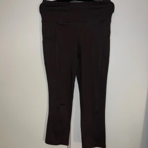 Svarta träningsbyxor  - Svarta leggings från KappAhl i stretchigt material med hög midja och praktiska sidfickor. Byxorna är tillverkade i 88% polyester och 12% elastan, vilket gör dem perfekta för träning eller chill. Modellen är croppad och sitter tight hela vägen.