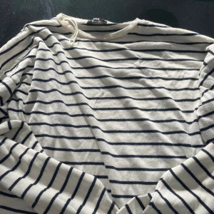 Randig långärmad tröja från C&A - Säljer en vit och marinblå randig långärmad tröja från C&A i storlek XS. Tröjan har klassisk rund halsringning och är tillverkad i mjukt stickat material, perfekt för en chill och stilren look.