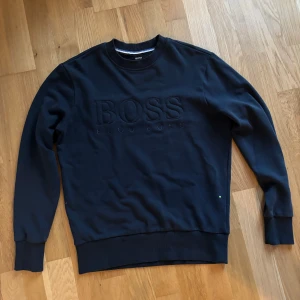 Mörkblå Hugo Boss sweatshirt  - Säljer min Mörkblåa Hugo Boss sweatshirt. Tröjan har bara används några gånger och är i mycket bra skick. Kommer va väldigt passande inför hösten/vintern och är mycket fin.