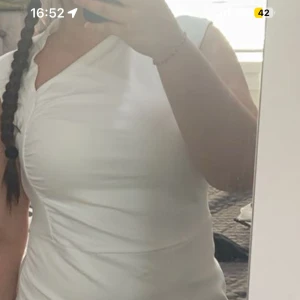 Vit omlottklänning med slits - Snygg vit omlottklänning med slits framtill och lätt rynk vid axeln. Klänningen har en figurnära passform som framhäver siluetten. Perfekt för dig som gillar stilrena och trendiga plagg. Använd endast i två tillfällen. 