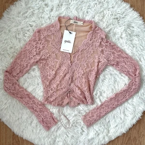 Rosa spetsbolero från Tipblu - Supersöt ljusrosa bolerotopp från Tipblu i genombruten spets med blommigt mönster. Nyskick med original ettikett. Storlek S (34-36).