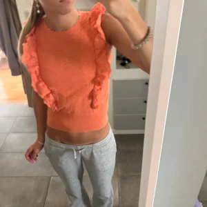 Orange volangtopp Holly & Whyte( Lindex) XS - Superfin orange topp från Holly & Whyte med volanger längs axlarna och ett snyggt stickat mönster. Ärmlös och croppad modell. Perfekt på vår och sommar