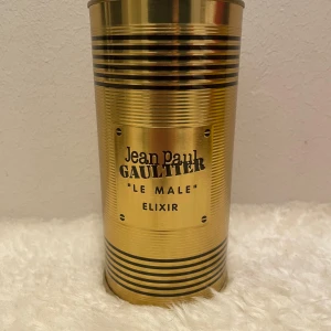 Jean Paul Gaultier Le Male Elixir - Exklusiv parfym i guldig metallflaska formad som en manlig torso med svarta ränder. Kommer i en matchande guldig burk med svarta detaljer och röd sammetsbas. En riktig statement-doft för dig som vill sticka ut. Säljer av min collection! 