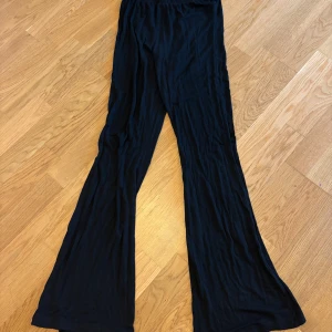 Svarta vida byxor med utsvängda ben - Svarta byxor med riktigt vida ben och skön, flowy känsla. Perfekta om du gillar en avslappnad och trendig stil. Mjukt material och elastisk midja gör dem superbekväma att bära hela dagen.