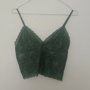 Grön spetslinnetopp från Bik Bok - Supersöt grön linnetopp från Bik Bok i spets med tunna axelband och v-ringad hals. Toppen har fina spetsdetaljer och blommönster i tyget, perfekt för att lyfta vilken outfit som helst. Säljes i storlek S.