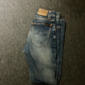 Blå jeans från Nudie Jeans - Snygga blå jeans från Nudie Jeans med klassisk femficksdesign och slitna detaljer. om ni beställer från bring kan jag leverera mycket snabbare.