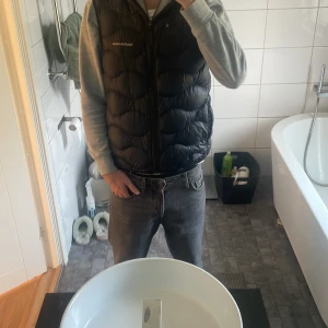 Svart dunväst från Peak Performance. - Säljer en svart dunväst från Peak Performance med quiltad design och hög krage. Västen har dragkedja framtill och två sidofickor. Perfekt att slänga över en hoodie för extra värme. Diskret logga på bröstet och stilren look. Fullt äkta, nypris: 2399 kr. Perfekt kap!