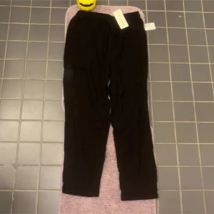 Svarta linnebyxor med snöre - Svarta mjukisbyxor från PanChaoHang med elastisk midja och snörning. Byxorna har en avslappnad passform och är tillverkade i mjukt material, perfekta för chill dagar. Enkla att matcha med hoodies eller t-shirts.