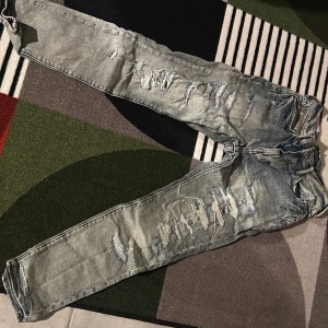 Ljusblå slitna skinny jeans - Snygga ljusblå jeans med slitningar och trasiga detaljer längs benen. Jeansen har en smal passform och klassisk femficksdesign. Perfekta för en avslappnad och trendig look.