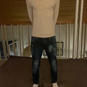 Mörkblå diesel slim fit jeans med slitningar - Säljer ett par mörkblå skinny jeans med snygga slitningar och tvättade detaljer. Jeansen har klassisk femficksdesign och smal passform som sitter tight längs benen. Perfekta för dig som gillar en modern och stilren look.