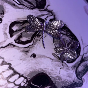 Silverfärgade ringar med blomma och trollslända - Två unika ringar i silverfärgad metall, en med en detaljerad trollslända och en med en stilren blomma. Båda ringarna har en cool och edgy vibe, perfekta för att sticka ut och ge din outfit en personlig touch. 