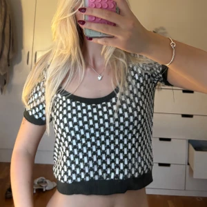 Grönvit rutig croppad topp - Säljer en croppad stickad topp med svartvitt rutigt mönster. Toppen har korta ärmar, rundad halsringning och ribbade kanter i svart. Perfekt för dig som gillar en trendig och bekväm stil. Ifrån Zara säljs inte längre 