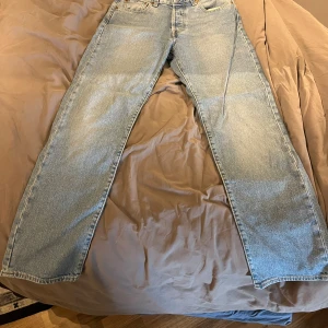 Levi's 501 ljusblå jeans W30 L30 - Klassiska ljusblå Levi's 501 jeans med rak passform och femficksdesign. Jeansen har den ikoniska läderpatchen bak i midjan och röd Levi's-tagg på bakfickan. Tillverkade i slitstarkt bomullsjeans, perfekt för en avslappnad stil. Aldrig använda.