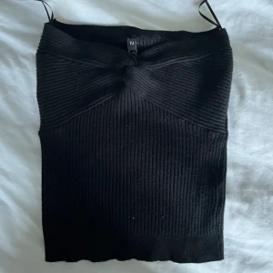 Svart ribbad tubtopp med twist - Säljer en svart ribbad tubtopp golden days