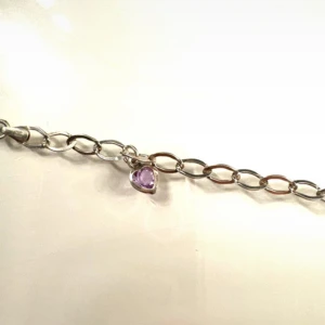 Silverarmband med lila hjärthänge - Stilrent silverarmband med ovala länkar och ett litet lila hjärthänge. Perfekt för dig som gillar enkla smycken med en söt detalj. Länkarna är medelstora och armbandet har ett klassiskt lås!