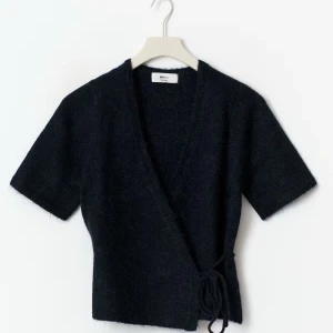 Marinblå omlottopp från Gina Tricot - Mysig marinblå omlottopp från Gina Tricot med kort ärm och knyt i sidan. Toppen har en v-ringad design och supersnygg passform. Går att knyta lite hur som.