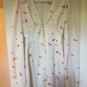 Vit blommig långklänning från Adoore - Superfin långklänning från Adoore i vit med små röda blommor använd 1 gång och säljer den för att jag inte har någon användning för den den är som ny original pris 1500