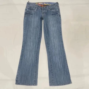 Blå bootcut jeans från Cron-X - Säljer ett par ljusblå bootcut jeans från Cron-X med snygga nitar på läderpatchen bak. Jeansen är tillverkade i 100% bomull och har klassisk femficksdesign. 