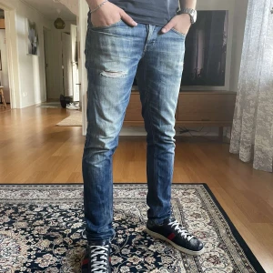 Dondup George Jeans, blå, stl 32 - Snygga Dondup jeans i modellen George i tvättad blå färg med slitningar och ljusa partier. Jeansen är i storlek 32. Modellen är ca 183 cm 78kg. Sydda hos skräddare vid skrevet så de är som normala (sista bilden).