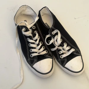 Svarta Converse sneakers med vit sula - Klassiska svarta Converse sneakers med vit tå och sula. Skorna har vit snörning, tydliga kontrastsömmar och rund tå. Tillverkade i bomullscanvas med gummisula. Perfekta för en avslappnad och cool stil.