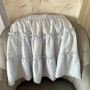 Blommig volangkjol från H&M - Supersöt ljusblå kjol från H&M med vita små blommor och flera volanglager. 🤍