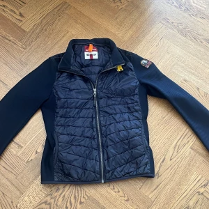 Svart quiltad jacka Parajumpers - Snygg mörkblå jacka i storlek M från Parajumpers med quiltad front och rygg, samt släta ärmar. Jackan har dragkedja framtill, hög krage och coolt PJS-märke på ärmen. Perfekt för dig som vill ha en sportig och stilren look. Passar mig perfekt som är 175. säljer på grund av att den inte används längre.