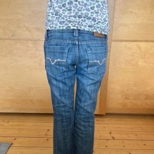Diesel bootcut jeans - Säljer ett par snygga blå jeans från Diesel med bootcut passform. Jeansen har broderade bakfickor. Jeansen är utsvängda(flared) och de har en låg midja. De är i perfekt skick och är i storlek 26. 
