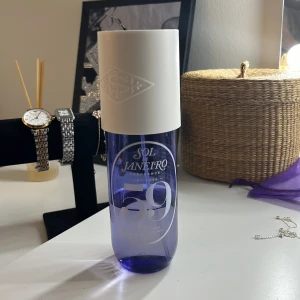 Sol de Janeiro Cheirosa 59 Parfym - Fräsch parfym från Sol de Janeiro i modellen Cheirosa 59. Flaskan är genomskinligt lila med vit spraykork och stor vit kork med logga. Modern och stilren design, perfekt att ha framme på sminkbordet. Doften är lätt och tropisk.