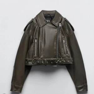 Grön skinnjacka från Zara - Snygg  Grön skinnjacka från Zara med croppad passform, bred krage och coola dragkedjedetaljer. Jackan har bälte i midjan och två fickor med dragkedja framtill. Perfekt för dig som vill ha en edgy look.                               Ordinarie pris:700kr